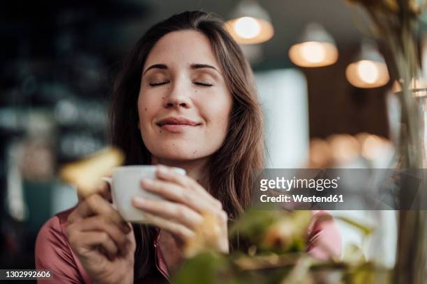 smiling businesswoman smelling coffee in cafe - donna occhi chiusi foto e immagini stock