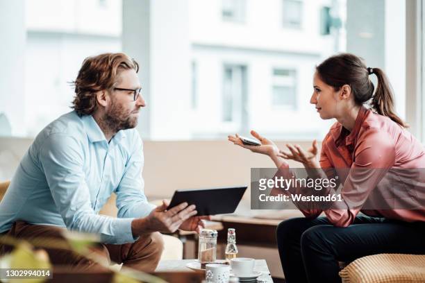 businesswoman explaining male colleague while discussing during meeting at cafe - explaining stock pictures, royalty-free photos & images