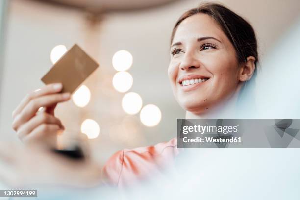 female professional looking away while paying through credit card at coffee shop - mann mit kreditkarte stock-fotos und bilder