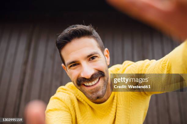 smiling man with mustache in yellow sweater taking selfie - bigode imagens e fotografias de stock