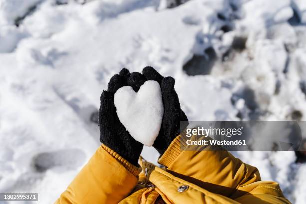 girl's hands holding heart shaped snow in park - yellow glove stock pictures, royalty-free photos & images
