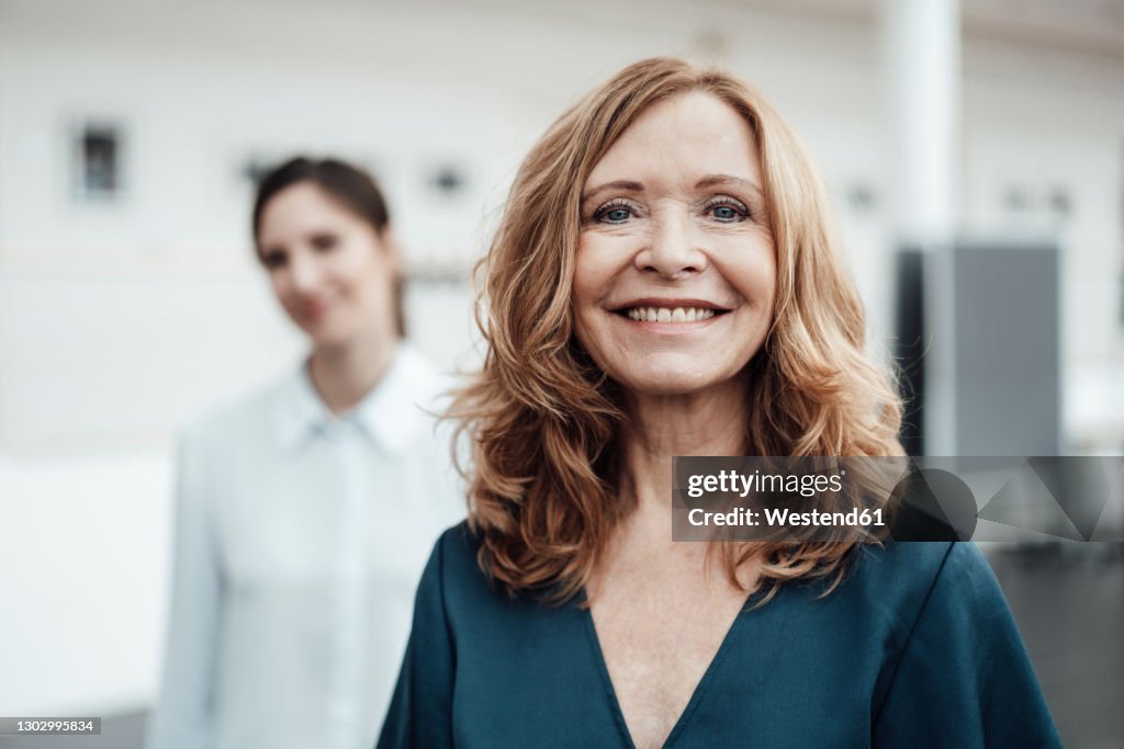 Smiling senior woman with female colleague in background at office