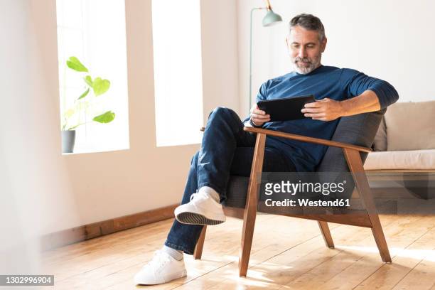 businessman using digital tablet while working at home - legs crossed at knee stock pictures, royalty-free photos & images