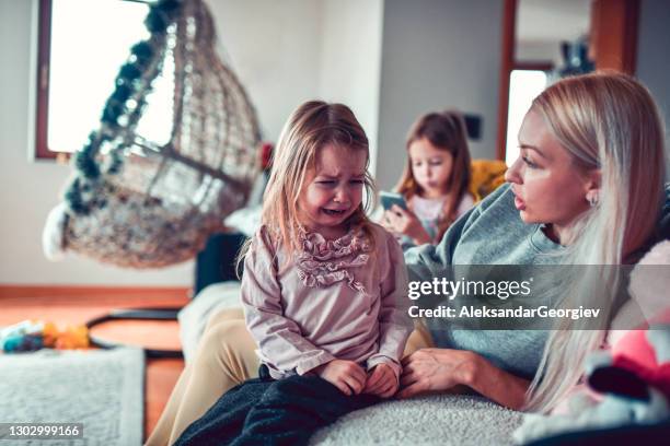 mother trying to calm crying child while the other one is using smartphone - jealous sister stock pictures, royalty-free photos & images