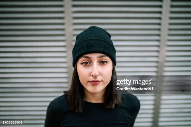 beautiful woman with gray eyes against metallic shutter - gorro de invierno fotografías e imágenes de stock