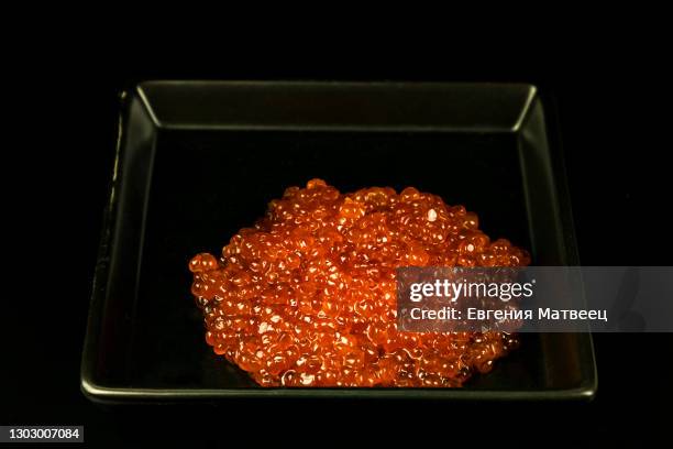 red salmon caviar big pile on black rectangular ceramic plate on black background. close up. - ikura bildbanksfoton och bilder