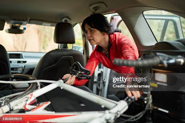 rijpe vrouwelijke atleet die het rennen fiets in rug van suv zet - inside car stockfoto's en -beelden