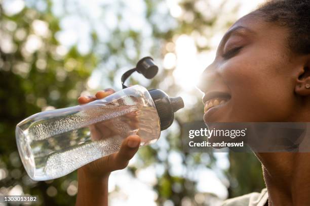 eine frau mit einer flasche wasser - woman drinking water from bottle stock-fotos und bilder