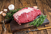 Fresh Raw brisket beef meat prime cut on a wooden  board with herbs. wooden background. Top view