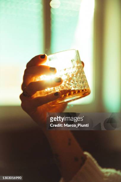 frauen hand hält ein alkoholisches getränk hinterleuchtete sonne - cognac glass stock-fotos und bilder
