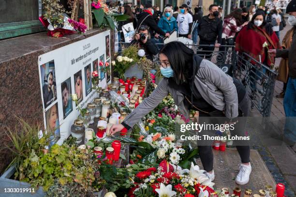 People lay candles and flowers at the Brothers Grimm Monument in front of the pictures and the names of the victims of the right-wing terrorist...