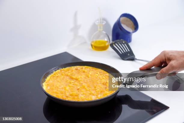 man cooking the mixture of eggs and fried potatoes into a pan to make spanish omeletteman cooking the mixture of eggs and fried potatoes into a pan to make spanish omelette - tortilla de patata fotografías e imágenes de stock