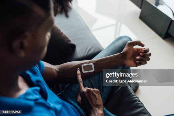 man using futuristic device on his arm - implante imagens e fotografias de stock