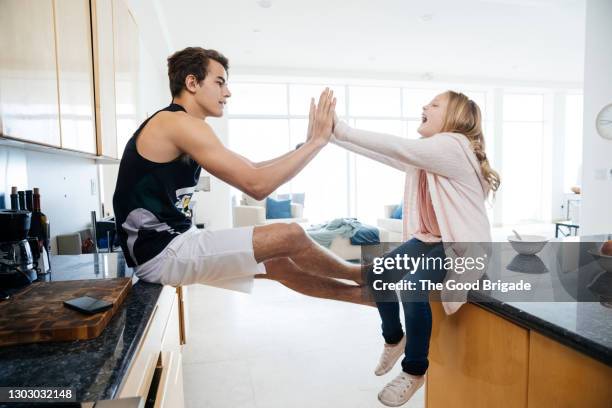 brother giving high five to sister in kitchen at home - clapping game stock pictures, royalty-free photos & images