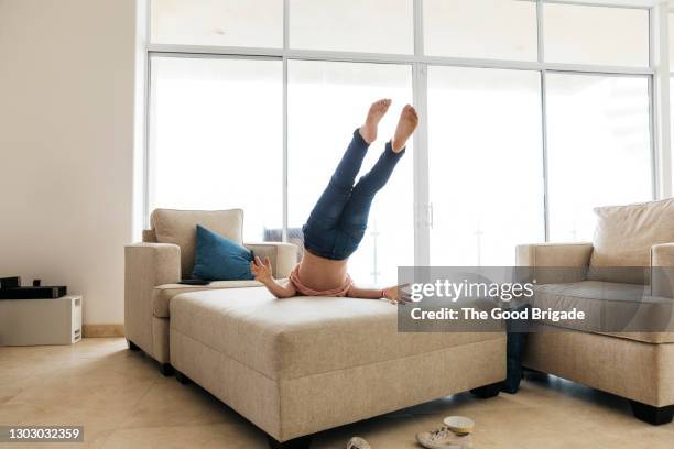 low section of playful girl falling on sofa at home - rear view hand window stockfoto's en -beelden