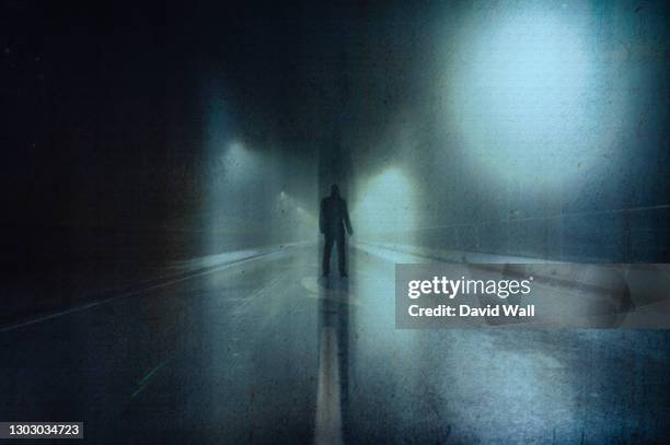 a moody figure, back to camera. standing in a street on a foggy winters night. with a grunge, artistic, edit - horror scene stock pictures, royalty-free photos & images