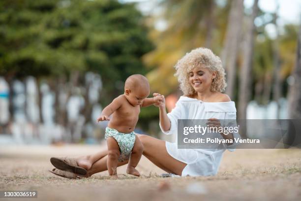 mamá enseñando a su hijo los primeros pasos - mothers day beach fotografías e imágenes de stock