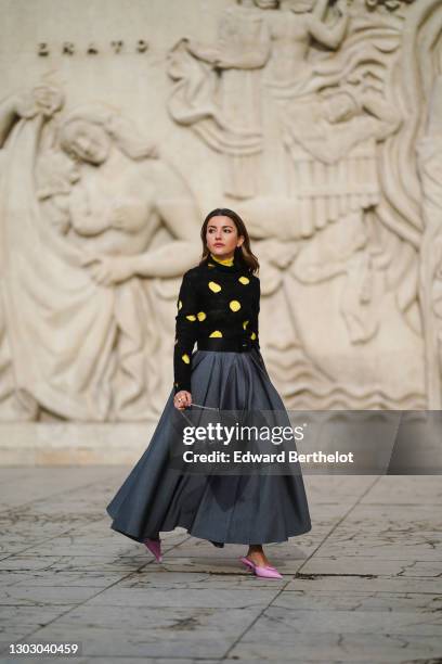 Alexandra Pereira aka Lovely Pepa wears a yellow turtleneck Prada top, a black wool Prada pullover with circular keyholes, a Prada belt, a gray Prada...