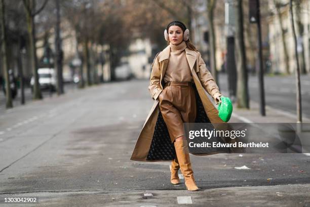 Alexandra Pereira aka Lovely Pepa wears beige fluffy ear muffs from Fendi, a beige wool turtleneck pullover / sweater from Zara, a beige trench coat...