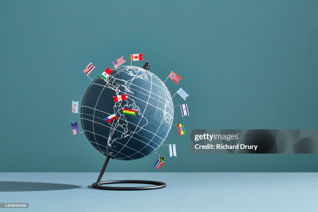 A world globe marked with several national flag pins