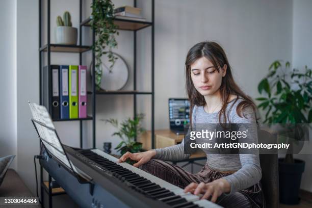 young beautiful woman playing piano at home during quarantine. - electric piano stock pictures, royalty-free photos & images