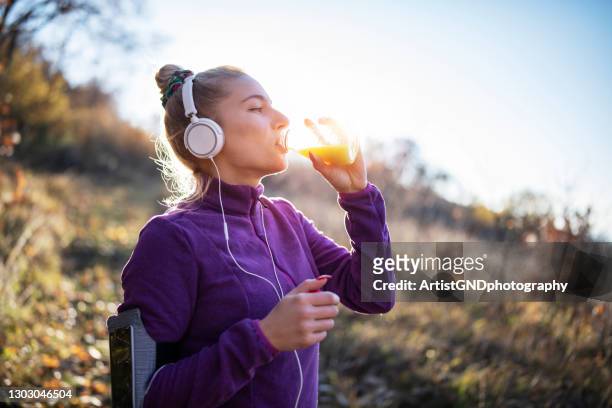 junge fitte frau, die eine pause vom joggen in der natur macht. - orange juice stock-fotos und bilder