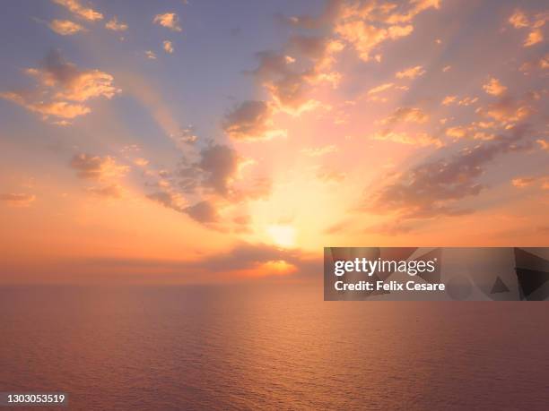 dramatic sky during sunrise over tranquil water. - sunrise photos et images de collection