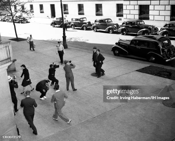 The New York County District Attorney Thomas E. Dewey walks towards the entrance of the District Attorney's office as photographers capture photos...