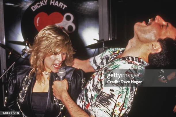 Singer Freddie Mercury of Queen performs a duet with Samantha Fox during a party at Kensington Roof Gardens in London, 12th July 1986. The event is...