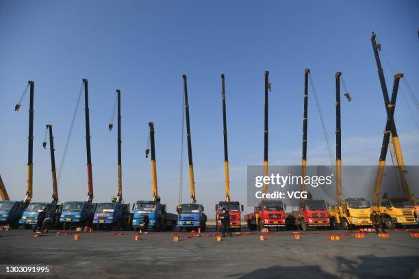 People set off firecrackers to pray for business booming in front of crane vehicles on the second working day after the Spring Festival holiday on...