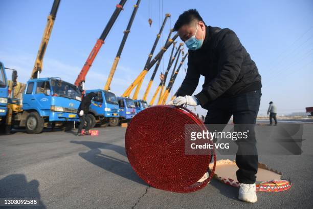 People set off firecrackers to pray for business booming in front of crane vehicles on the second working day after the Spring Festival holiday on...
