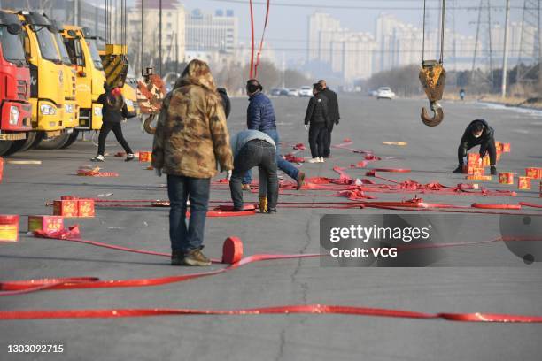 People set off firecrackers to pray for business booming in front of crane vehicles on the second working day after the Spring Festival holiday on...