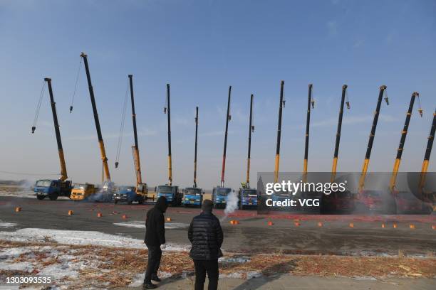 People set off firecrackers to pray for business booming in front of crane vehicles on the second working day after the Spring Festival holiday on...