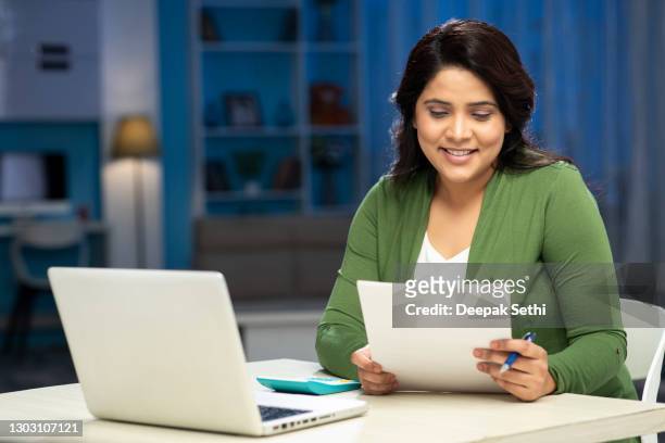 mid adult women examine document and calculating expenses using laptop at home, stock photo - mid adult women stock pictures, royalty-free photos & images