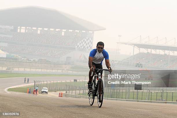 Team Lotus reserve driver Karun Chandhok of India cycles the track as preparations continue during previews to the Indian Formula One Grand Prix at...