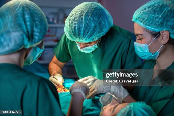 surgeons operating patient for breast implant. team of doctors are in scrubs at operating room. - performing arts event stockfoto's en -beelden