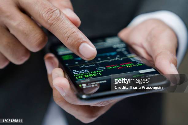 businessman using a mobile phone to check stock market data - stock market crash stock-fotos und bilder