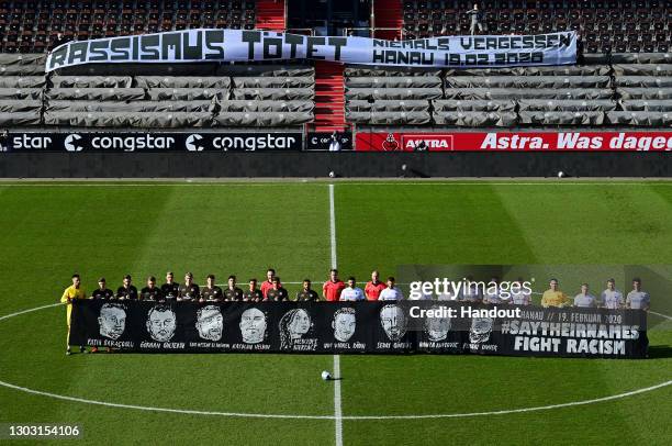 In this handout image provided by Witters Sportfotografie, players of FC St. Pauli and SV Darmstadt 98 hold a banner to commemorate the victims of...