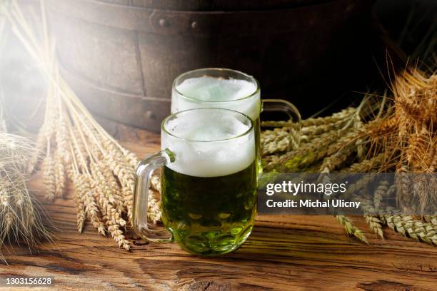 green beers on a wooden table, in the back of the original oak barrel and wheat cob. this beer is traditionally served on st. patrick's day, or also during easter times in europe. - german greens party stock pictures, royalty-free photos & images