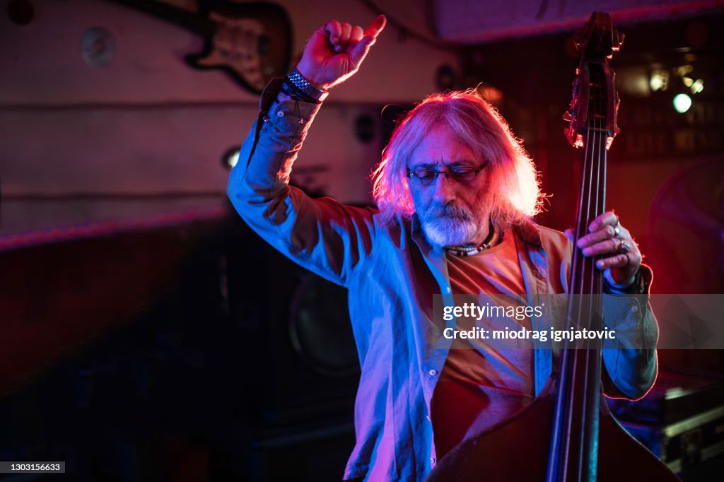 Senior double bass player enjoying the feeling when he performing on stage