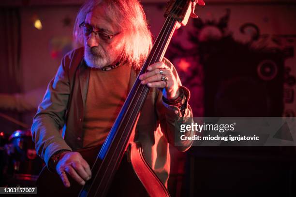 senior-mann spielt kontrabass auf der bühne mit seiner band auf gig - bass drum stock-fotos und bilder