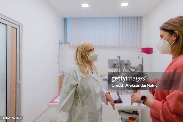 female doctor with a protective face mask talking with a patient - mammogram stock pictures, royalty-free photos & images