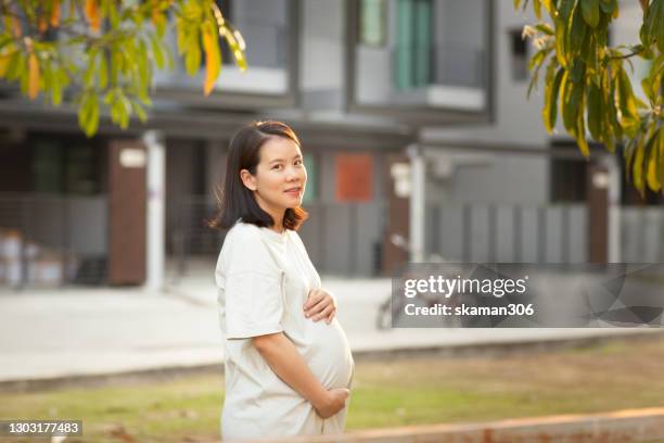 south east asian female pregnant touching newlife inside abdomen with urban building scene outdoors - south east asia stock-fotos und bilder