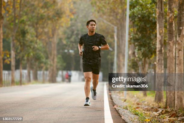 asian sportman jogging and checking smart watch between workout jogging outdoor - men exercising stock pictures, royalty-free photos & images