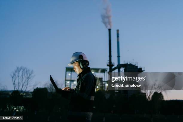 asian engineer working in factory at night - worker inspecting steel foto e immagini stock