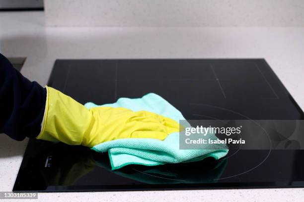 close-up of hand with rubber glove cleaning induction stove with rag - trapo de limpiar el polvo fotografías e imágenes de stock