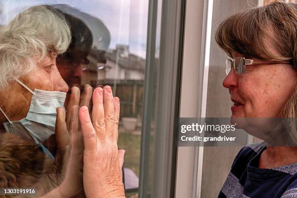 concerned woman visiting a high risk elderly woman quarantined in her home due to covid19, corona virus - prison window stock pictures, royalty-free photos & images