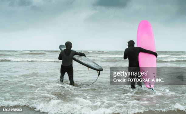 young couple getting ready to go in to water to surf - lake ontario stock pictures, royalty-free photos & images