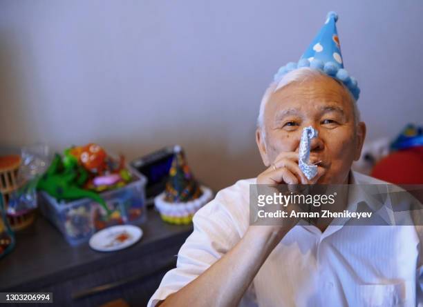 senior man wearing party hat and playing horn blower at the birthday party - party horn blower bildbanksfoton och bilder