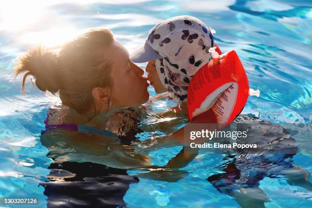 cute boy 2-3 y.o. playing with his mother in the swimming pool at summer sunny day - brazaletes acuáticos fotografías e imágenes de stock